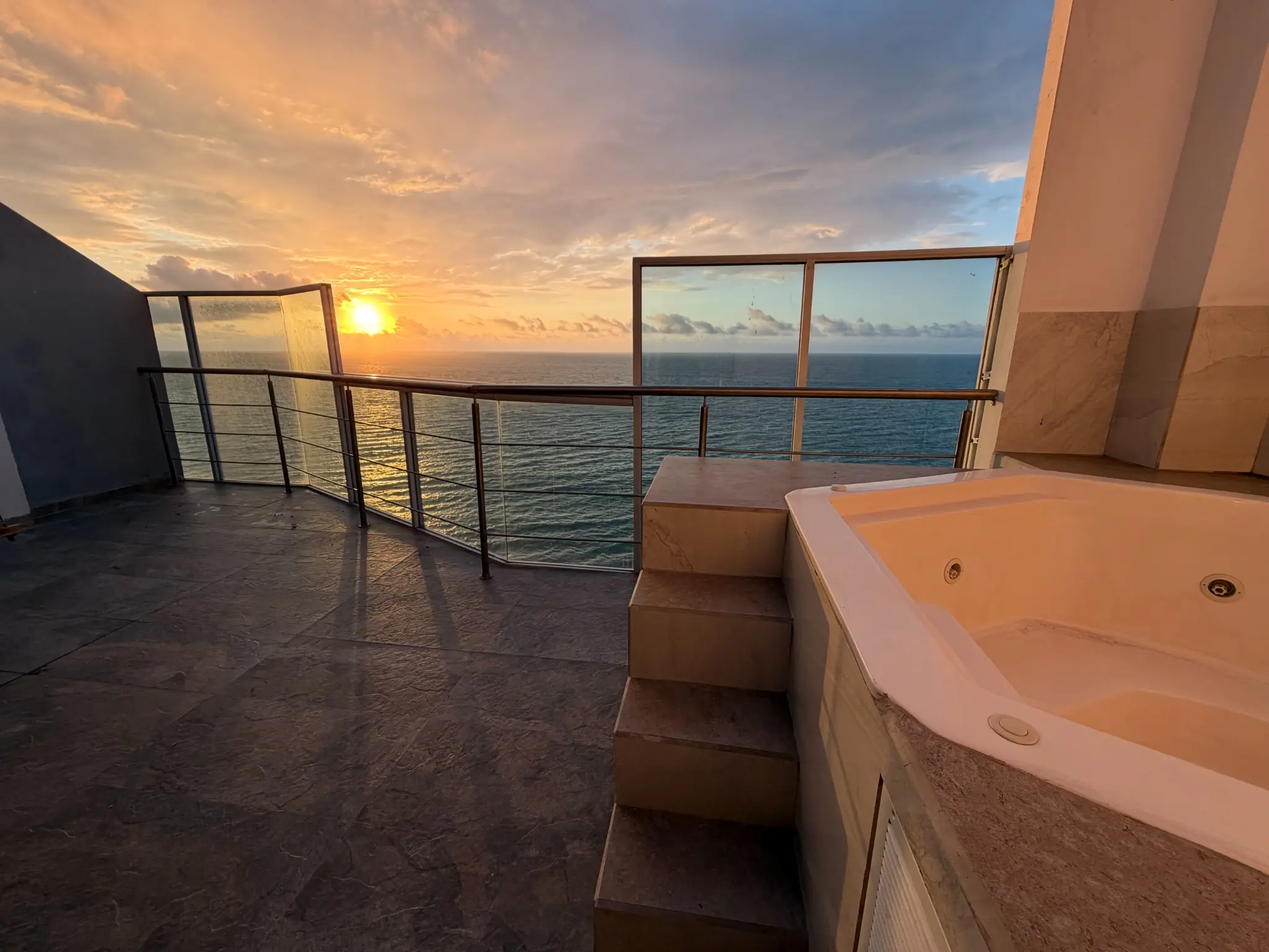 Terraza privada con jacuzzi y puesta de sol sobre el océano